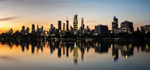 The reflections of the melbourne city skyline at dusk in the still water of albert park
