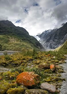 Images Dated 11th January 2020: Rocks covered with moss and red lichens, in the back glacier tongue of Franz Josef
