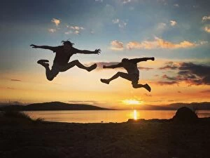 Jodie Griggs Collection: Silhouette of two men jumping into the sunset sky