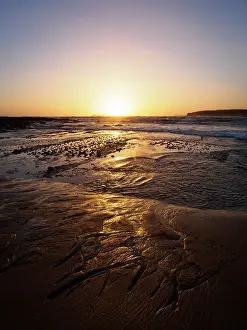 Striking Sunset Prints: Sun setting over waves and sandy beach in Victoria, Australia