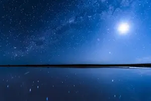 Vivid blue night sky, Milky Way galaxy and Full Moon shining in a starry sky, reflecting over Lake Tyrrell, Australian landscape