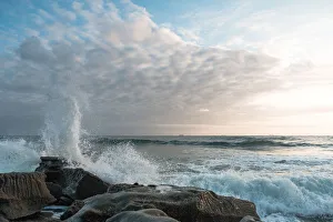 White clouds with waves crashing on a rock formation at Moffat Beach, Queensland White clouds with waves crashing on a rock formation at Moffat Beach, Queensland